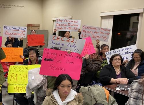 中国侨网纽约华裔家长在第22学区教育理事会开会现场高举抗议牌。（美国《世界日报》/黄伊奕 摄）