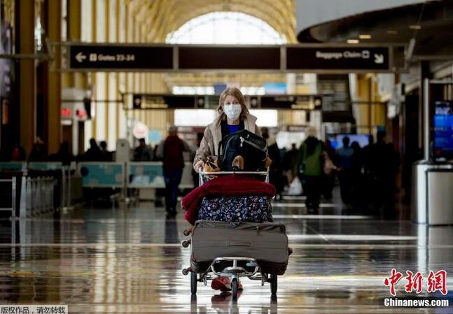 一名戴着口罩的乘客走过里根华盛顿国家机场的航站楼。(<a target='_blank'  data-cke-saved-href='http://www.chinanews.com/' href='http://www.chinanews.com/' >中新网</a>)