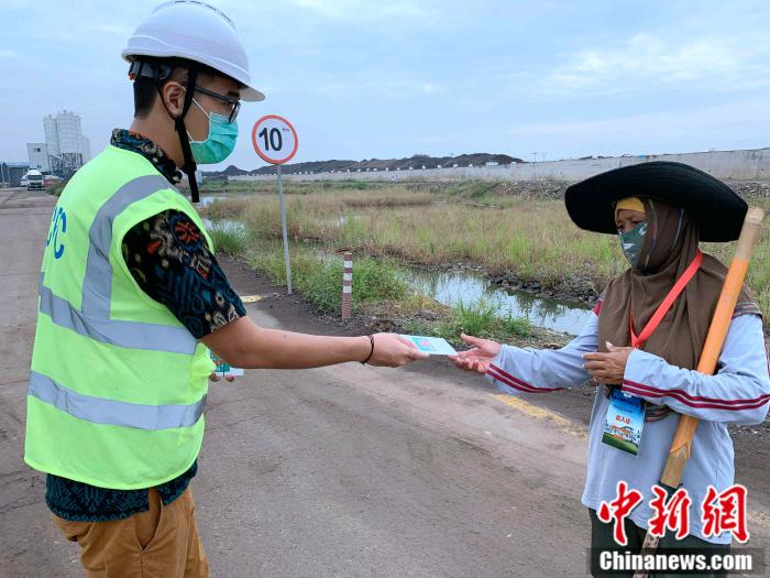 图为华裔小伙子林淼雄(左)为项目部保洁员送去防疫手册。沈超 摄