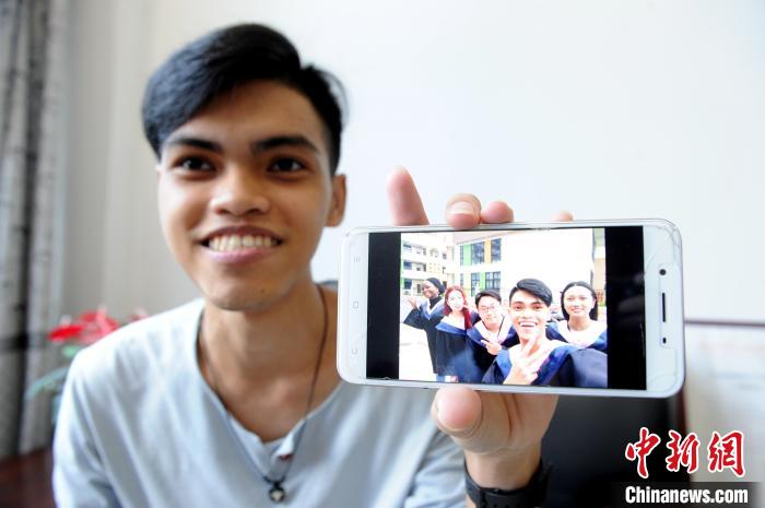 菲律宾青年夏贝尔打开手机展示毕业照。　张金川 摄
