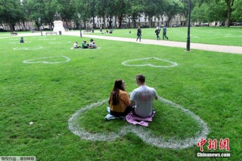 当地时间2020年7月8日，英国布里斯托尔，艺术家在皇后广场的草地上画出心形图案，敦促人们保持社交距离。