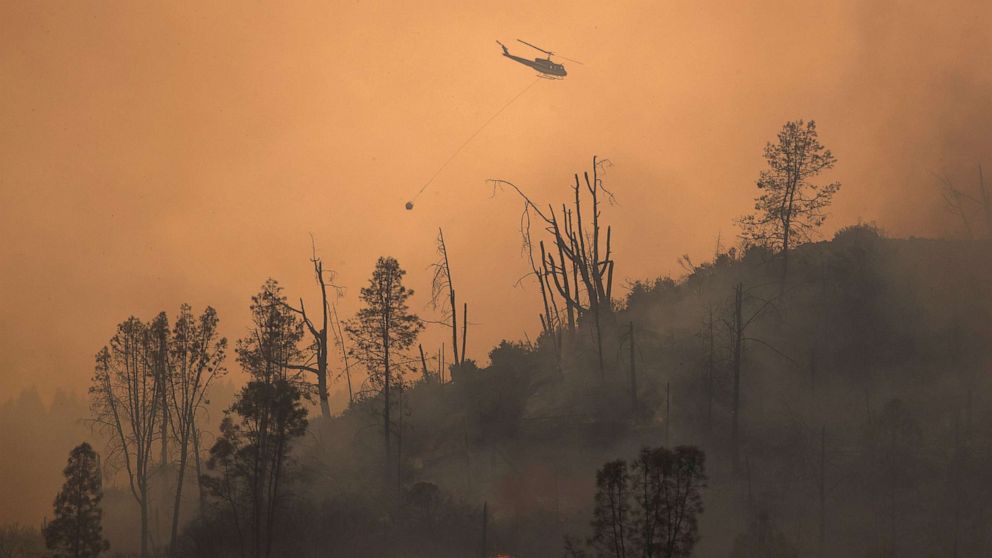PHOTO: A helicopter and crew releases water to extinguish a section of the LNU Lightning Complex Fire near Middletown, Calif., Aug. 24, 2020.