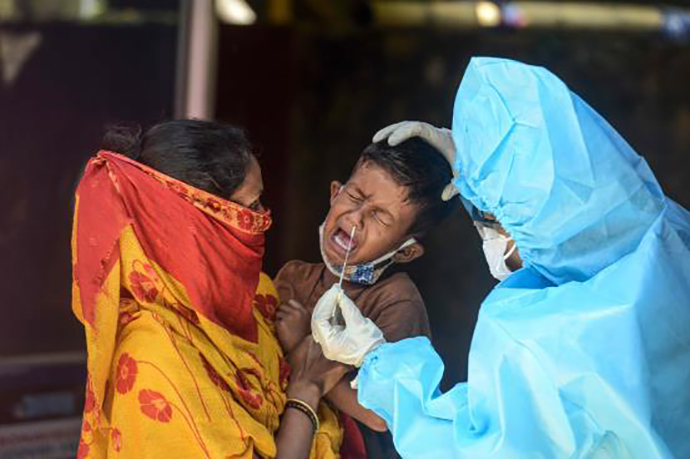 8月26日，在印度西里古里一处新冠病毒检测中心，一名工作人员给一个孩子进行检测采样。新华社 图