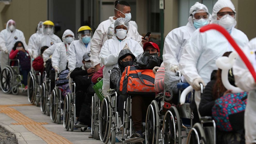 PHOTO: Health workers wheel out a group of about 80 COVID patients who have been discharged and are being released from the former Athletes Village built for Lima's Panamerican Games.