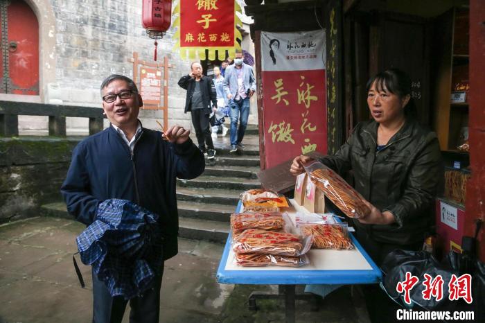 俄罗斯金砖电视台副总裁王睿(左)在周子古镇品尝当地小吃。　王磊 摄