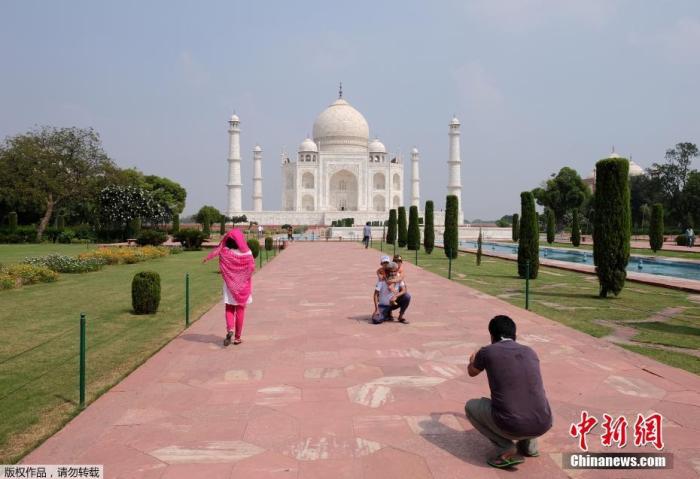 资料图：当地时间9月21日，印度泰姬陵重新对外开放。图为游客游览泰姬陵并拍照留念。