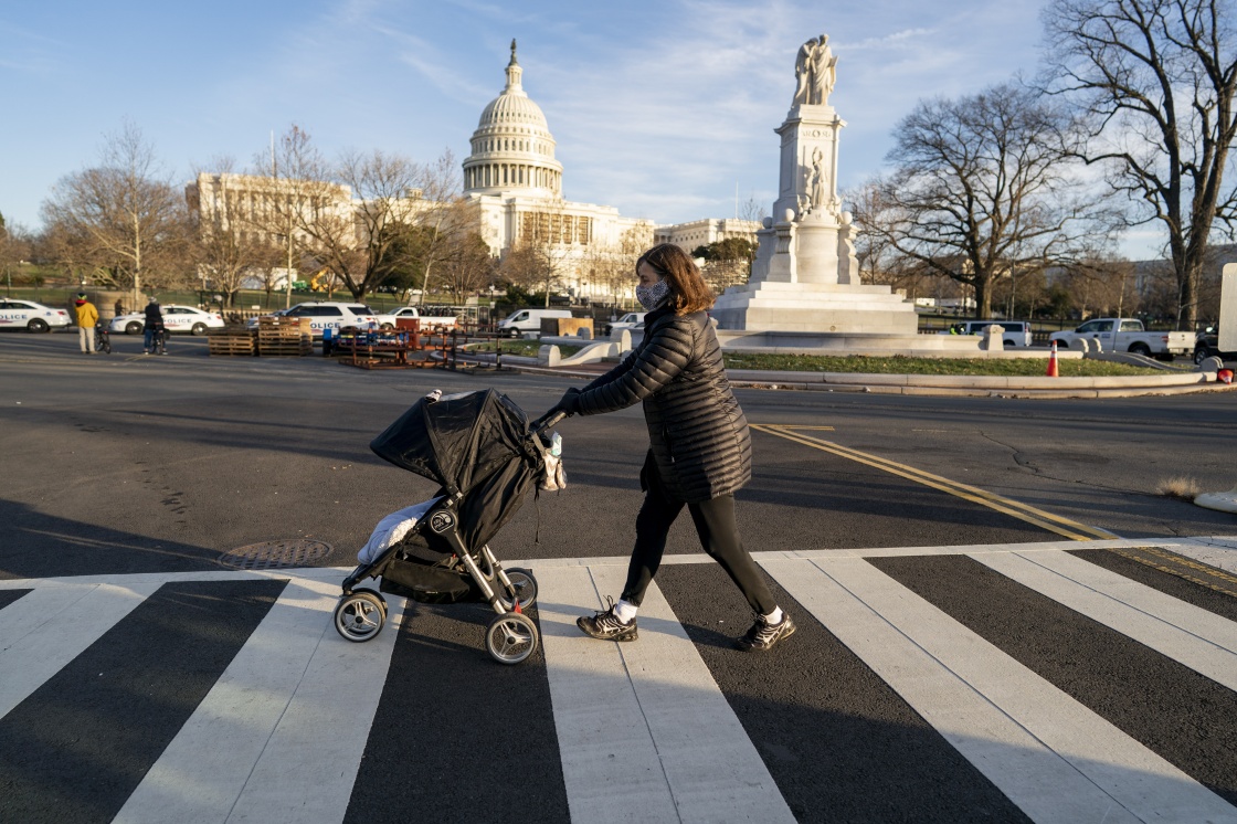 1月7日，在美国首都华盛顿，一名戴口罩的女子推着婴儿车经过国会大厦。新华社 图