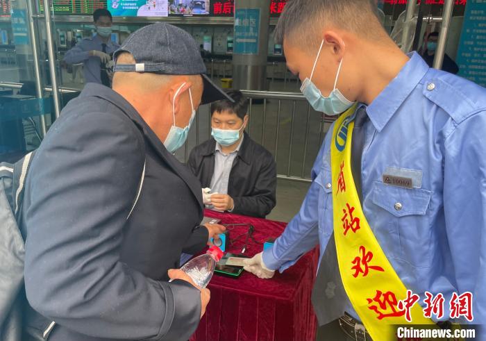 在广东省客运站，一位长者旅客在工作人员的指引下，把身份证放在识别设备上方。　蔡敏婕 摄