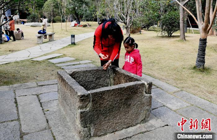 一对母女俩观看位于冶山春秋园内的一口古井。　记者刘可耕 摄