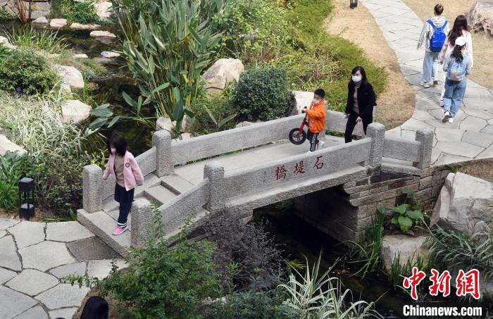 前来游览的市民从冶山春秋园内的石提桥上通过。　记者刘可耕 摄