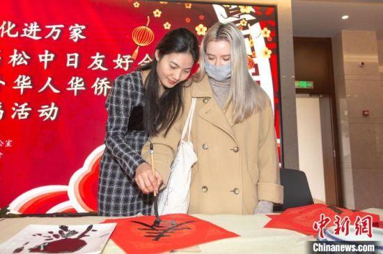 2月6日上午，在南昌高松中日友好会馆，一位外籍人士在书画家的指导下写“春”字。　刘力鑫 摄