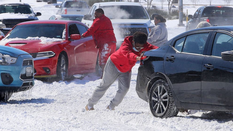 PHOTO: People push a car free after spinning out in the snow on Feb. 15, 2021, in Waco, Texas.