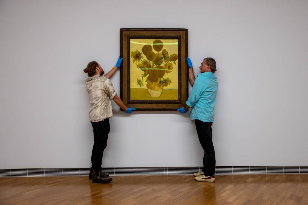 堪培拉国家美术馆工作人员正在悬挂梵高的《向日葵》