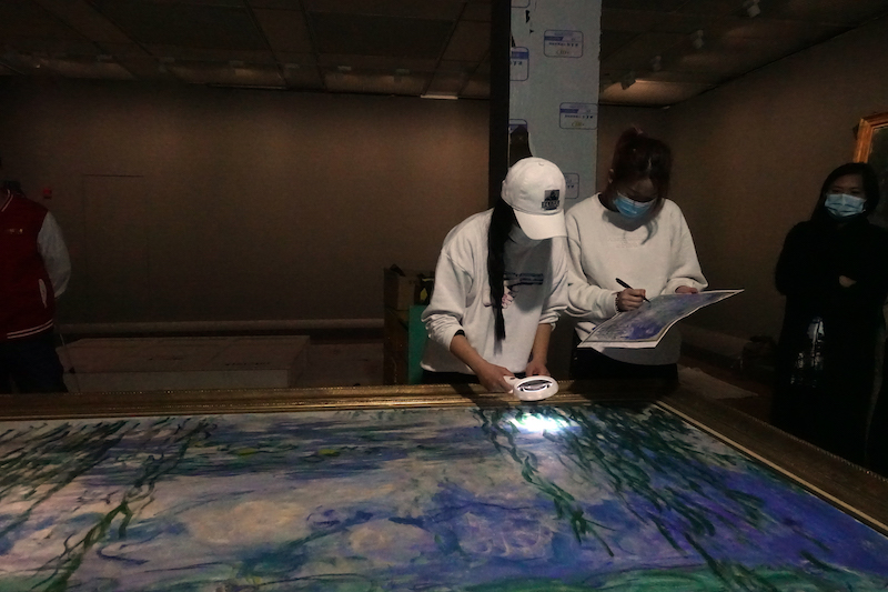 布展现场，工作人员正在检测莫奈作品《睡莲》