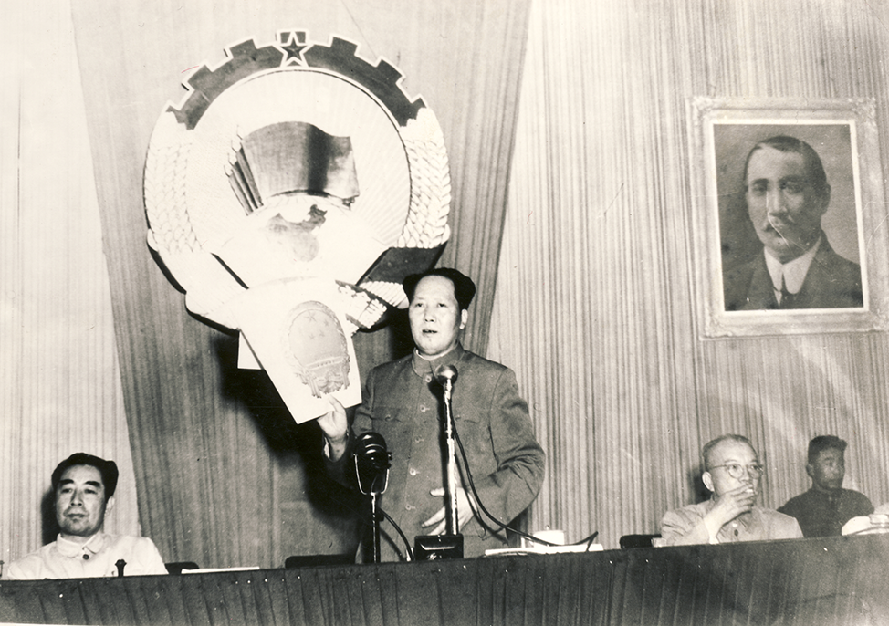 1950年6月全国政协会上毛主席举起梁思成领导的清华大学营建系国徽设计小组设计的国徽方案以示通过