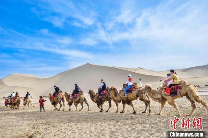 图为游客骑骆驼畅游鸣沙山，观赏敦煌丝路风情，大漠壮美风光。　王斌银 摄