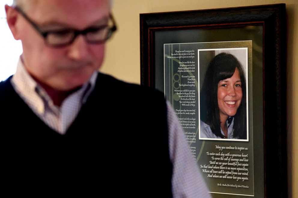 PHOTO: In this May 1, 2019, file photo, John Erickson walks by a photo of his daughter, Heidi Firkus, alongside a poem 