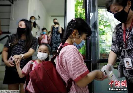 图为2020年6月2日，新加坡校重新开学，幼儿园学生进教室前用洗手液消毒。