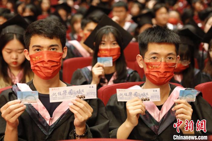 华侨大学毕业生们展示学校提供毕业礼包三件套。　刘沛 摄