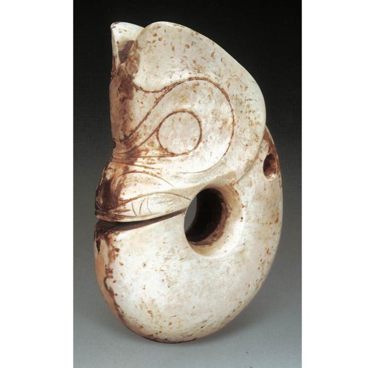 这件白玉猪龙是辽宁省博物馆从辽宁建平县征集的，它猪首蛇身，肥头大耳，嘴巴前突，獠牙外露，身体卷曲如环，是红山先民创造的抽象化神灵。