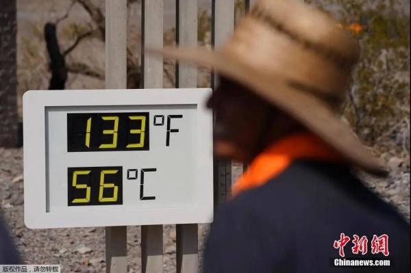 资料图：当地时间7月11日，美国加州死亡谷国家公园迎来高温。图为民众在看温度指示器