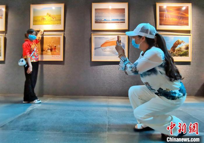 图为西宁市民铁红青为10岁的女儿和摄影作品拍照。　祁增蓓 摄
