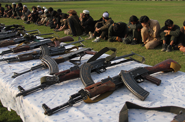 一群于2019年向阿富汗政府军投降的极端组织成员，他们面前是其使用的武器。