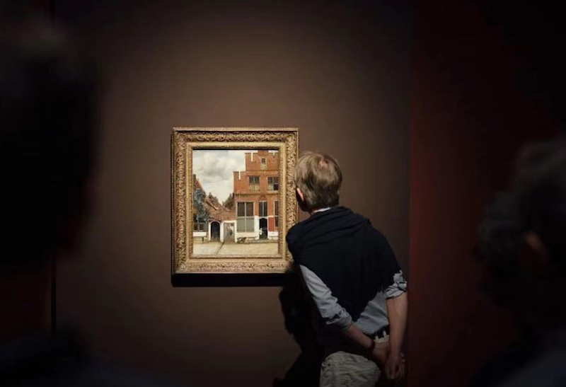 展览现场，观众在荷兰阿姆斯特丹国立博物馆藏、维米尔的《小街》前