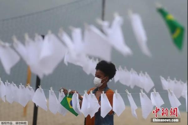 资料图：当地时间10月8日，巴西里约一民间组织为纪念死于新冠肺炎的60万巴西人，在科帕卡帕纳海竖起桅杆，并在上面悬挂600条白色手帕，活动组织者称这600条白手帕除了纪念病亡的60万同胞。