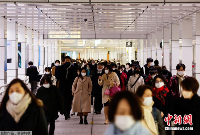 日本民众戴着口罩走过东京一座火车站的大厅。