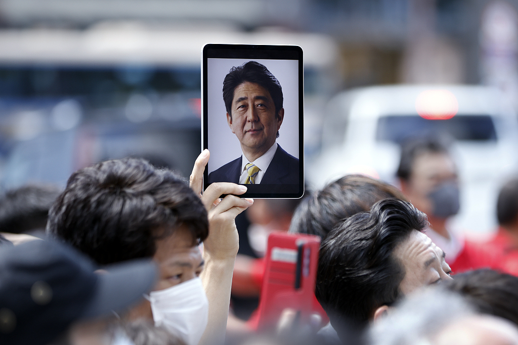 当地时间2022年7月9日，日本横滨举行的一场竞选活动中，一名与会者手持平板电脑，上面展示着日本前首相安倍晋三的照片。人民视觉  资料图