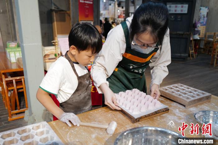 中国侨网6月2日,小朋友在工作人员指导下制作定胜糕。正值端午假期,在杭州手工艺活态馆内,各式传统手工制作技艺吸引民众进行体验。中新社记者 张煜欢 摄