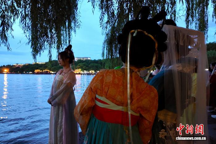 中国侨网8月6日，游客身穿传统服饰在西湖边留影。当日，浙江杭州，傍晚的西湖景色美如画，吸引游客打卡。中新社记者 钱晨菲 摄